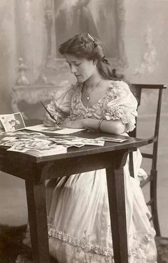 an old black and white photo of a woman sitting at a table with a book