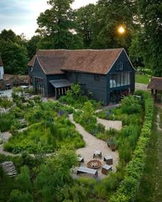 an aerial view of a house surrounded by trees and bushes with benches in the foreground