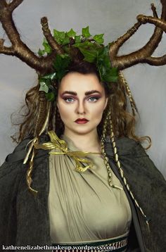 a woman with horns on her head wearing a dress and green leaves in her hair