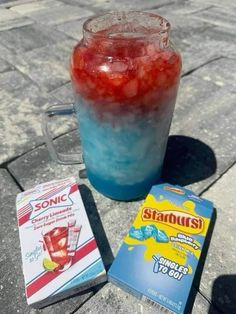 a drink and some snacks sitting on a table outside in the sun, with an unopened box next to it