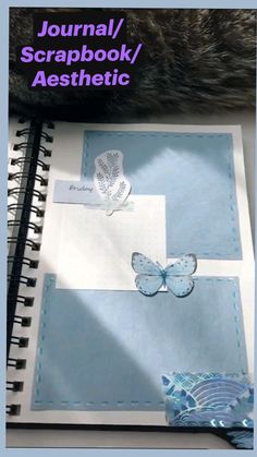 an open notebook with butterflies on it and a cat's paw next to it