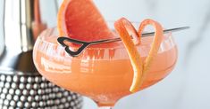 a close up of a drink in a glass with an orange slice on the rim