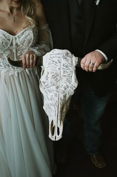 a man and woman holding a fake cow skull with writing on it's side