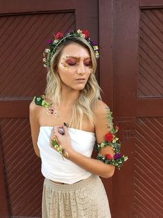 a woman with flowers painted on her face and arm around her body wearing a white top