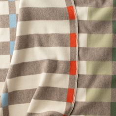 closeup of the zippers on an unisex baby's blanket, which is striped with orange and blue squares