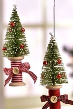 two small christmas trees hanging from wooden poles with bows and buttons on them, decorated with ribbon