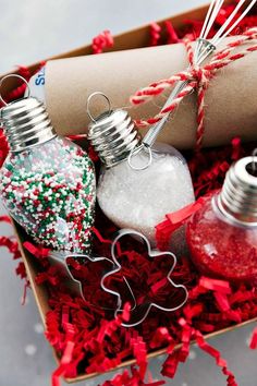 an open box filled with christmas ornaments on top of red shredded paper and twine