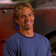 a smiling man standing in front of a red truck