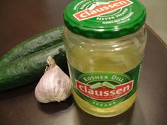 a pickle and jar of cucumbers sitting on a table