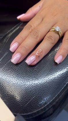 a woman's manicured nails and ring on top of a black purse in front of her