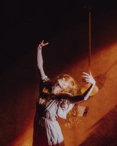 a woman standing in the dark holding her arms up