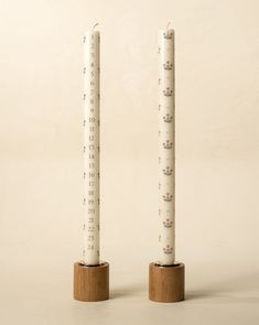 two tall candles with cats on them sitting on wooden bases