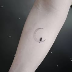 a cat sitting on the moon tattoo on the left inner arm, and behind it is a small black cat