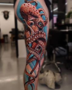 an octopus tattoo on the leg of a man with blue and red ink, in a room