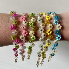 a woman's arm with several bracelets made out of beads and flowers on it