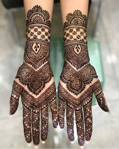 two hands with henna tattoos on them, one is showing the intricate pattern and the other has an ornate design