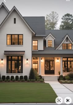 a large white house with lots of windows and lights on it's front porch