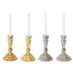 three gold and silver candlesticks are lined up next to each other on a white background