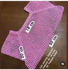 two pieces of crocheted clothing with tags on them, one is pink and the other is purple