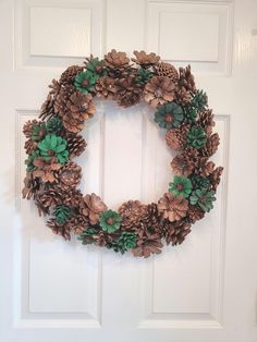 a wreath made out of pine cones and green leaves