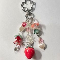 a key chain with charms attached to it on a white surface, including a strawberry