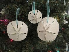 two white ornaments hanging from a christmas tree