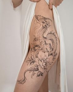 a woman's thigh with flowers and a dragon tattoo