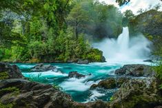 a large waterfall in the middle of a forest filled with rocks and water flowing down it's sides