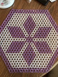 a purple and white beaded object sitting on top of a wooden table