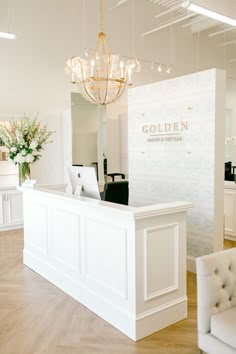 a white reception area with chandelier and chairs