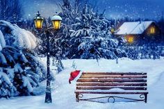 a wooden bench sitting in the middle of a snow covered park next to a lamp post