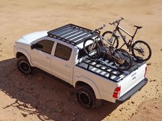 a white truck with two bikes on the back and one bike mounted to the bed