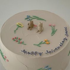 a birthday cake decorated with two teddy bears and flowers on it's side, in the shape of a circle