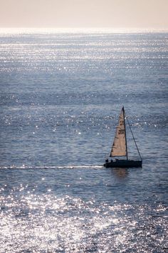 a small sailboat floating on top of a large body of water in the ocean