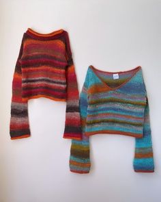 two knitted sweaters sitting next to each other on top of a white surface