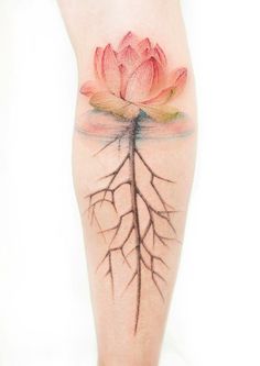 a woman's leg with a pink flower and tree roots tattoo on the side