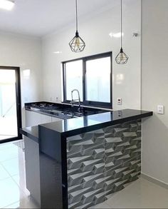 a kitchen with an island in the middle and two pendant lights hanging from the ceiling