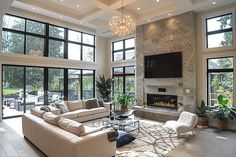 a living room filled with lots of furniture next to large windows and a flat screen tv mounted on the wall