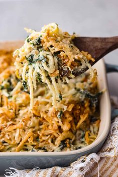 a casserole dish with broccoli and cheese being lifted from the casserole