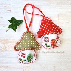 three christmas ornaments hanging from a red ribbon on a white wooden table with a green leaf