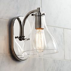 a light that is on the side of a wall next to a tiled wall with a glass shade