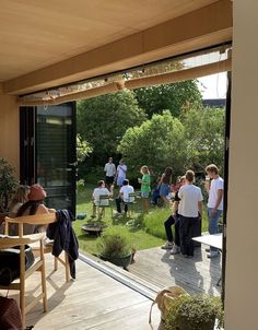 a group of people are gathered outside on the deck in front of an open door