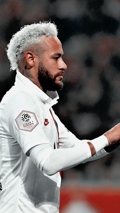 a close up of a soccer player holding his hand out to the side with an audience in the background