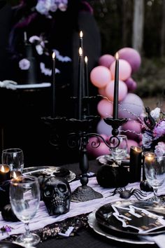 a table set for halloween dinner with candles and decorations