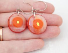 a pair of earrings with orange and white designs on them