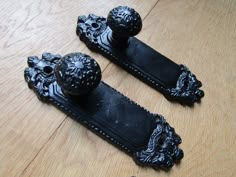 two black door knobs sitting on top of a wooden floor next to each other