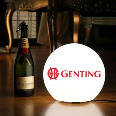 a bottle of wine sitting next to a lighted ball with the word genting on it