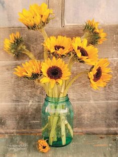 a vase filled with yellow sunflowers sitting on top of a table