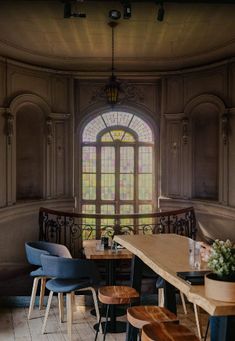 an empty restaurant with wooden tables and chairs in front of a large stained glass window