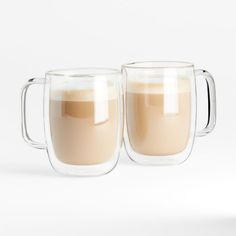 two clear mugs filled with liquid sitting next to each other on a white surface